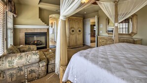 Un dormitorio con una cama grande, una zona de estar con cojines estampados, una chimenea y una cama con dosel.