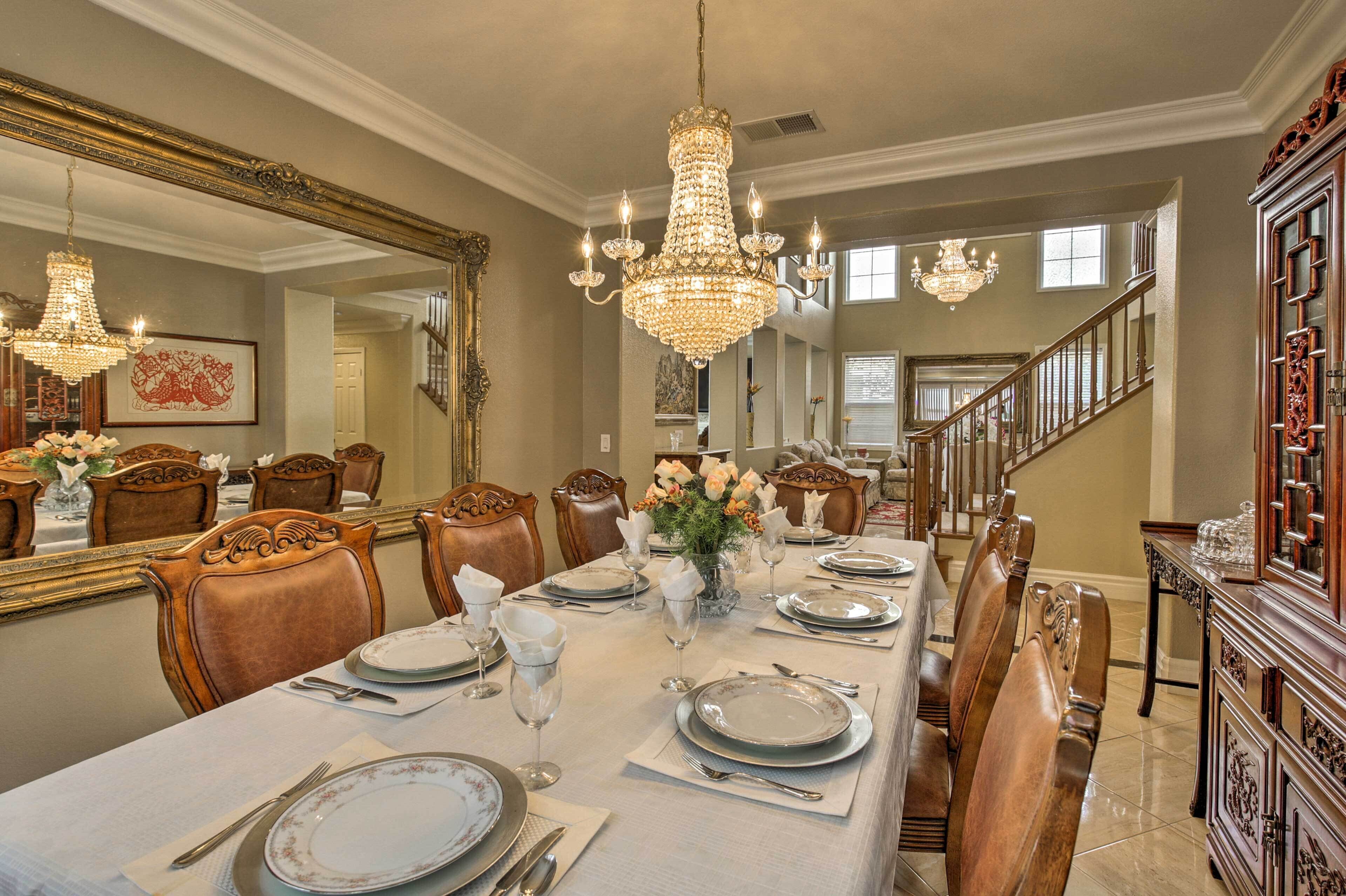 Une salle à manger élégante, avec une grande table dressée pour six personnes, des chaises richement décorées, un lustre et un grand miroir.