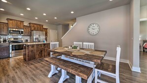 Eine moderne Küche mit Holzkorpusen, einem Edelstahlkühlschrank und einer Essecke mit Holztisch und Bank.