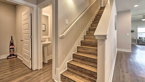 Eine Treppe mit Holzdielen und weißen Wänden, die zu einem Badezimmer mit Waschbecken und Spiegel führt.