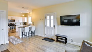 A modern kitchen with white cabinets, a central island, and a dining area with bar stools. - Downtown Buena Vista Condo: Steps From Everything! (Buena Vista)
