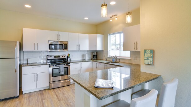 A modern kitchen with white cabinets, stainless steel appliances, granite countertops, and a central island with bar seating. - Downtown Buena Vista Condo: Steps From Everything! (Buena Vista)
