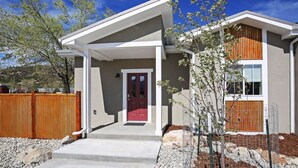 A modern two-story house with a red door, a covered front porch, and a fenced garden area. - Downtown Buena Vista Condo: Steps From Everything! (Buena Vista)