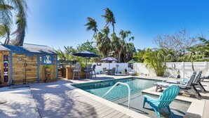 Ein Poolbereich mit Liegestühlen, einer Holzterrasse und Palmen.