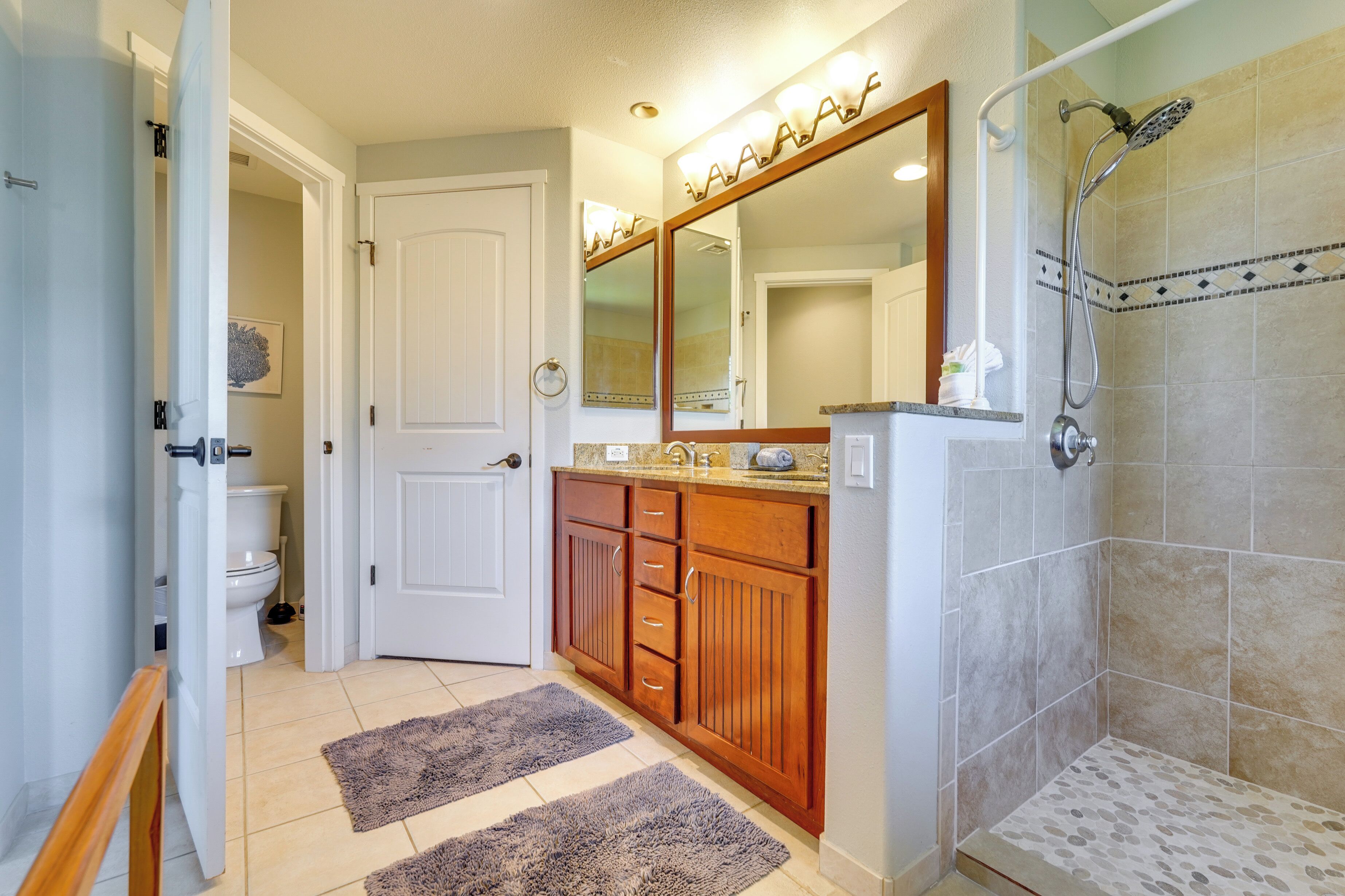 A bathroom with a shower, toilet, and vanity with a mirror.