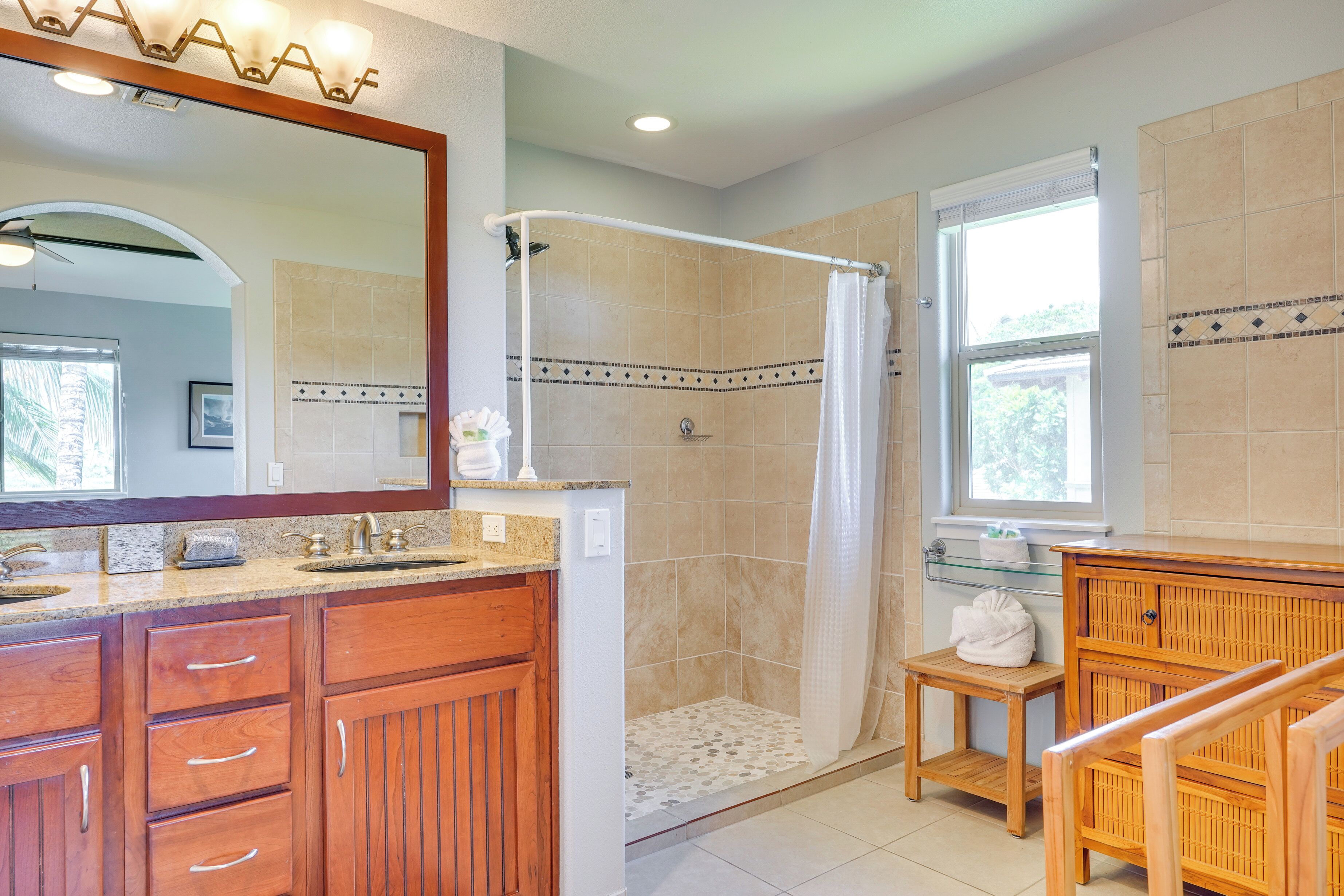 A bathroom with a shower, vanity, and a mirror.