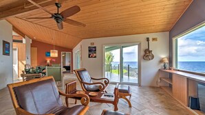 A spacious living area with wooden furniture, a ceiling fan, and a view of the ocean. - Direct Oceanfront, Big Island Home (Keaau)