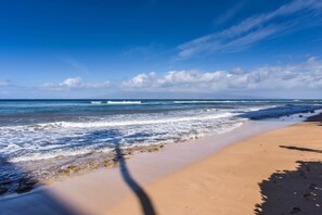 A beach with a clear sky, waves, and footprints.