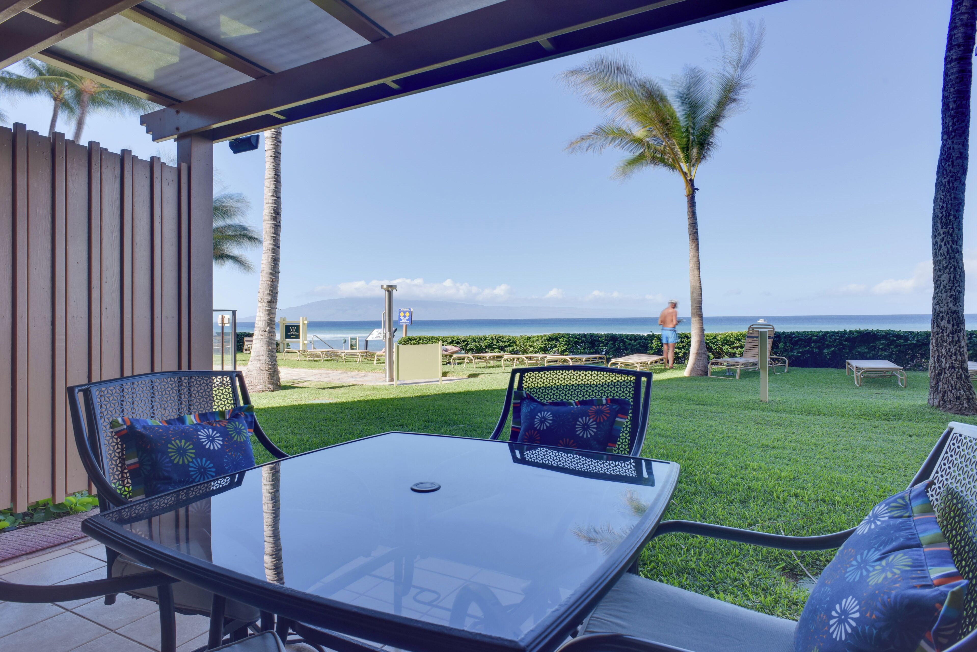 A glass-top table with chairs and a view of the ocean.