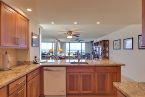 A kitchen with wooden cabinets, a granite countertop, and a built-in dishwasher.