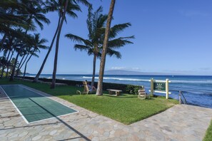 A pool area with a view of the ocean, palm trees, and a caution sign.