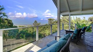 Un espacio de estar al aire libre cubierto con vistas a un paisaje exuberante.