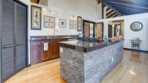 Una cocina amplia con una isla grande, armarios de madera y salpicadero de piedra.