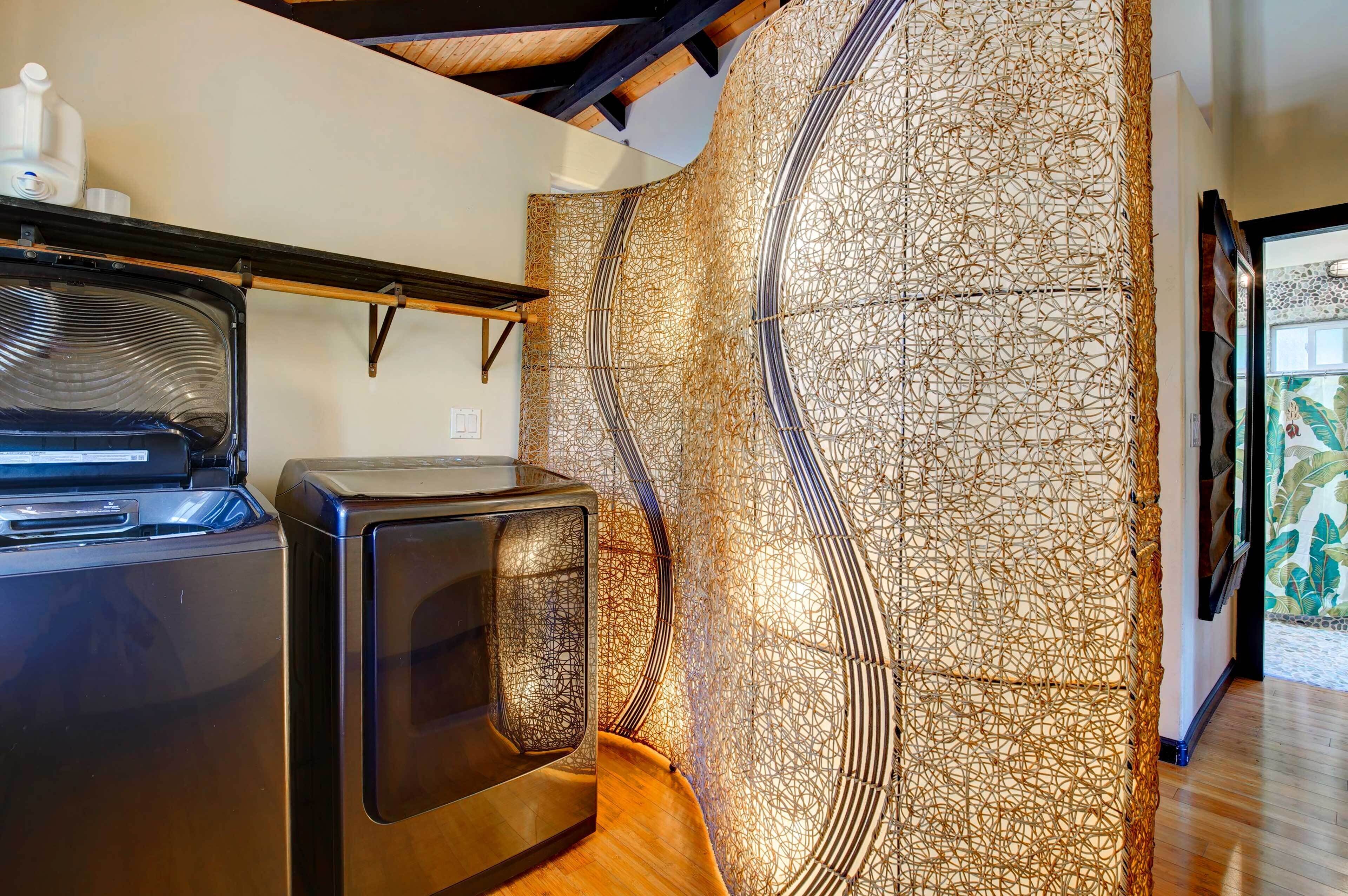 A laundry area with a washing machine and dryer, a wooden bench, and a decorative wall with a woven pattern.