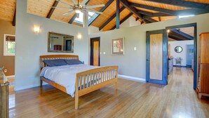 Un dormitorio amplio con una cama de madera, un ventilador de techo y un espejo grande.