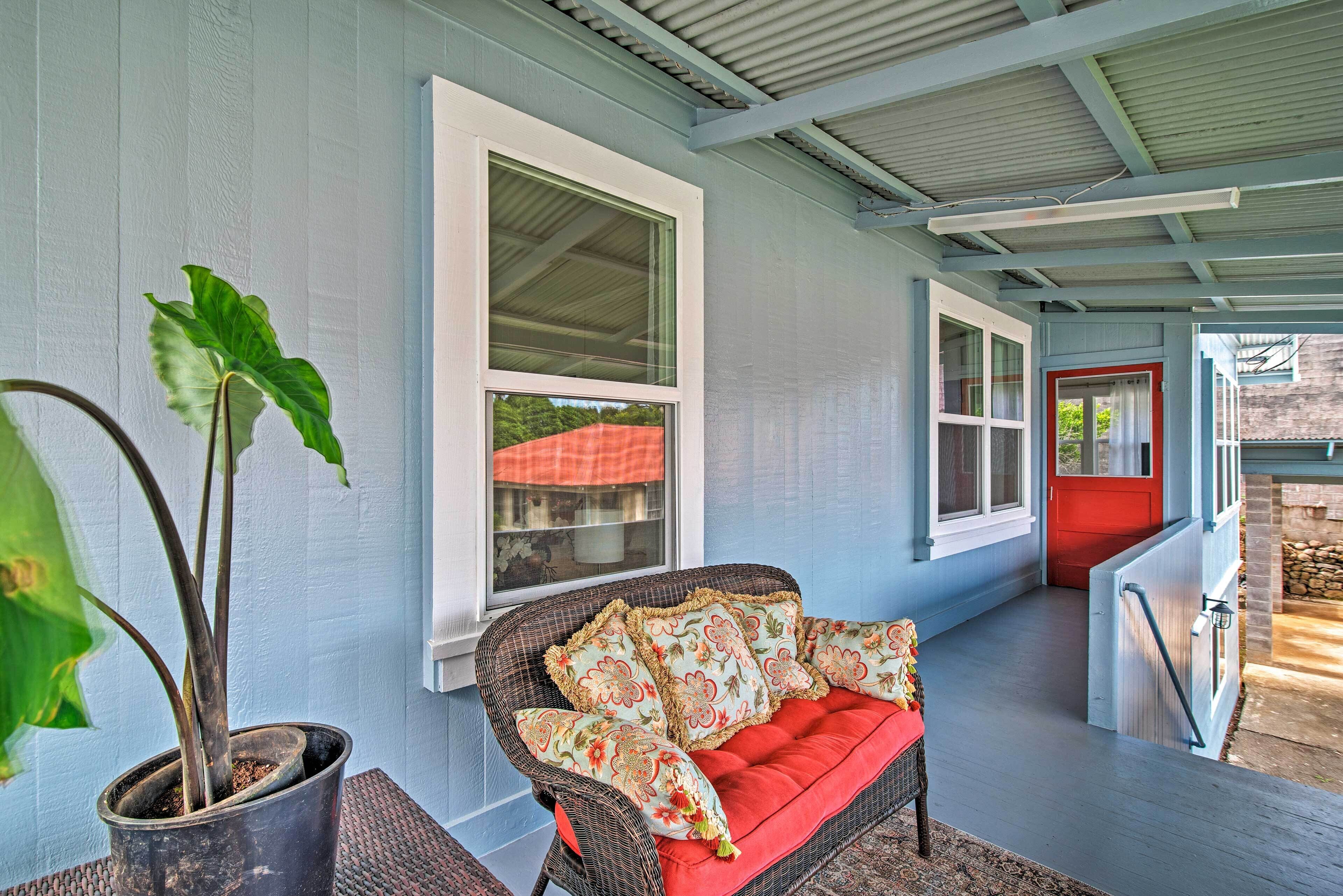 A covered porch with a wicker chair and a potted plant.