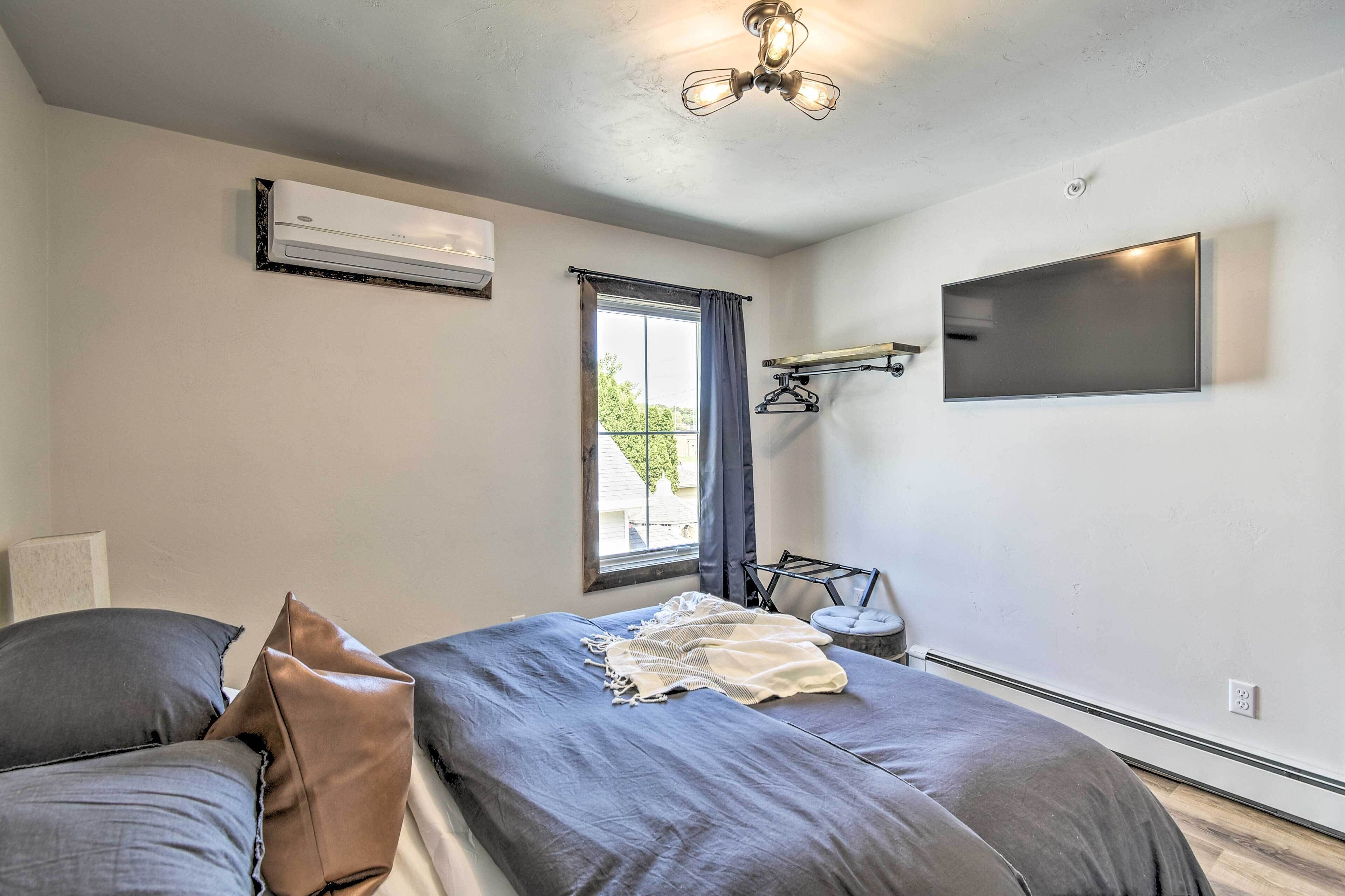 Une chambre avec deux lits, un ventilateur de plafond, un téléviseur fixé au mur et une fenêtre avec des rideaux.
