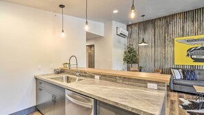 Cozinha moderna com bancada de madeira, eletrodomésticos de aço inoxidável e iluminação pendente.