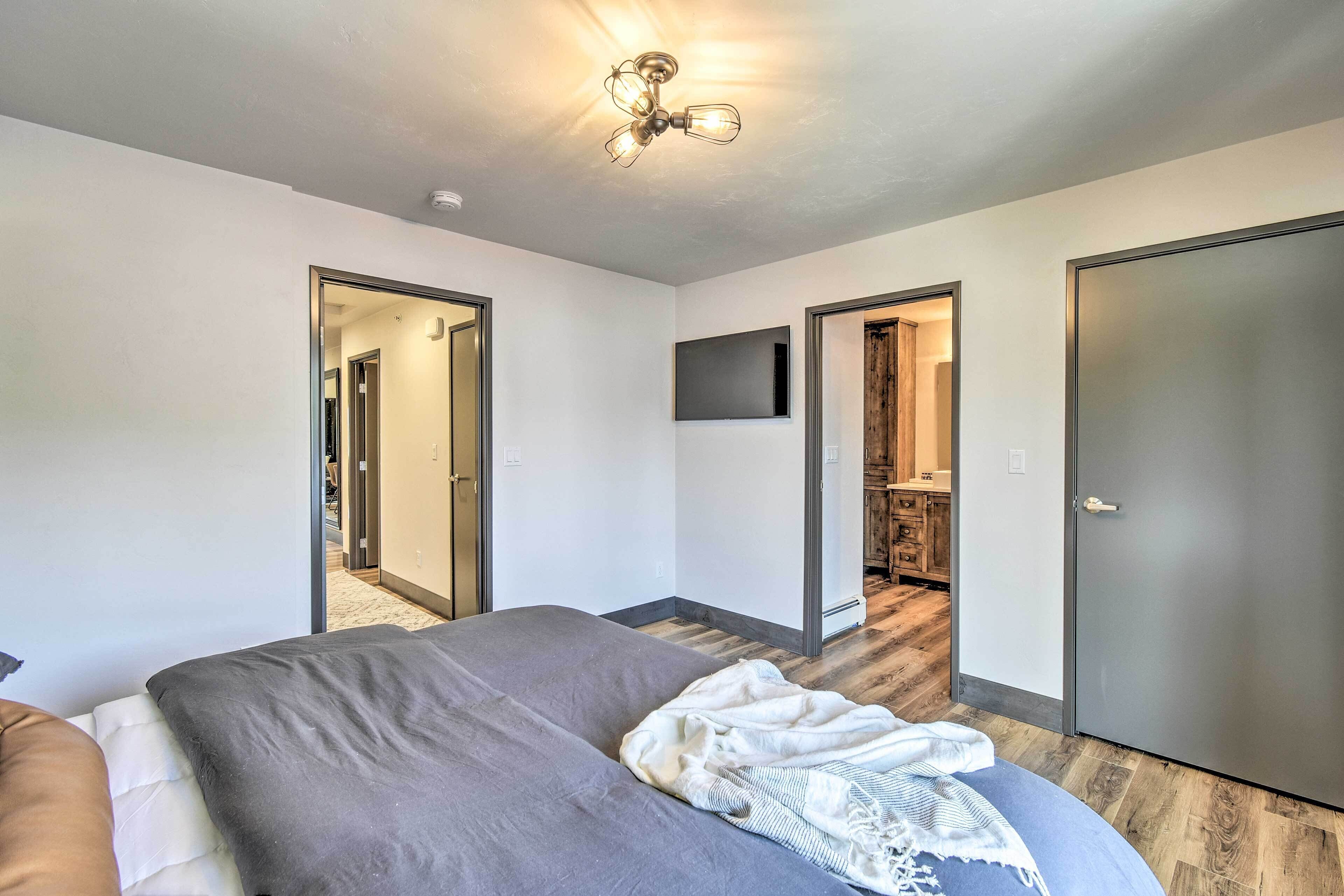 A bedroom with a bed, a ceiling fan, a TV, and a wardrobe.