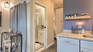 Une salle de bain moderne avec une douche, un lavabo et des toilettes. On y trouve une petite table avec des chaises et un luminaire suspendu.