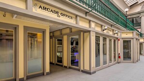 L’immeuble Arcade Office, avec une enseigne au-dessus de l’entrée, un extincteur sur le mur et une rambarde verte à l’étage supérieur.