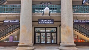 L’entrée d’un immeuble, avec des enseignes indiquant « Impulse Hair Designs » et « Jacky’s Galaxy ».