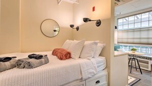 Une chambre d’hôtel avec un lit, un bureau, une chaise, un miroir et une fenêtre.
