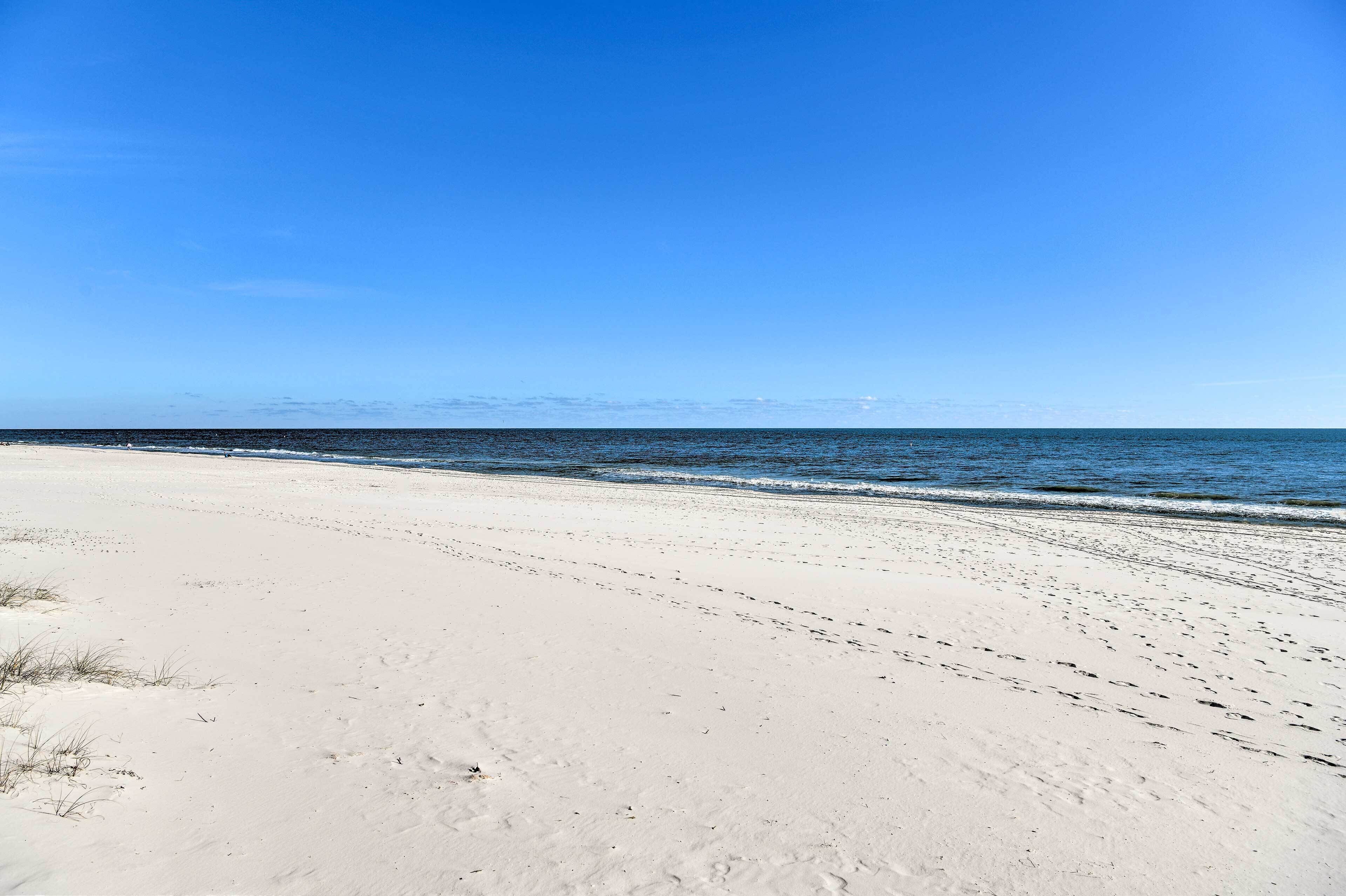A beach with white sand and a clear blue sky.