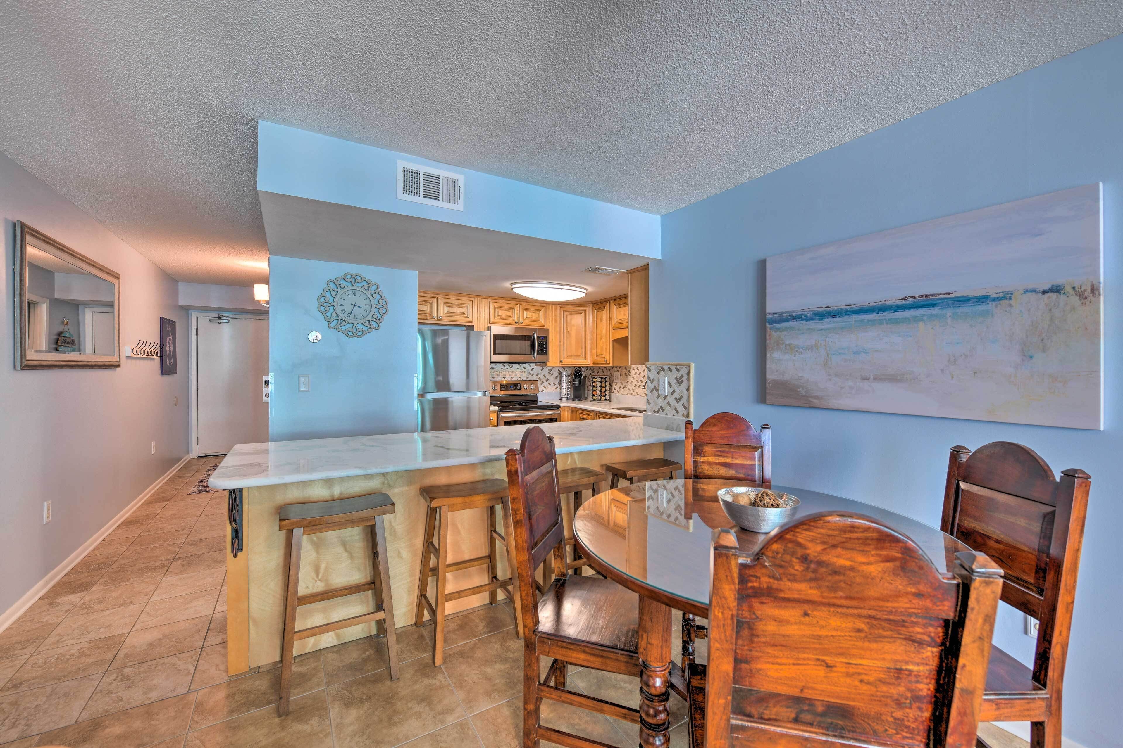 A modern kitchen with a central island, wooden chairs, and a dining table.