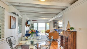 A spacious living area with a glass dining table, modern furniture, and a view to the outside.