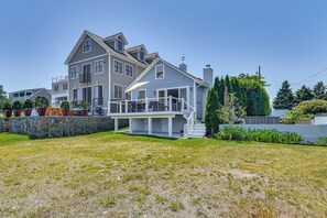 A large two-story house with a covered porch and a stone wall. - Coastal Portsmouth Home w/ Bay Access Near Newport (Portsmouth)