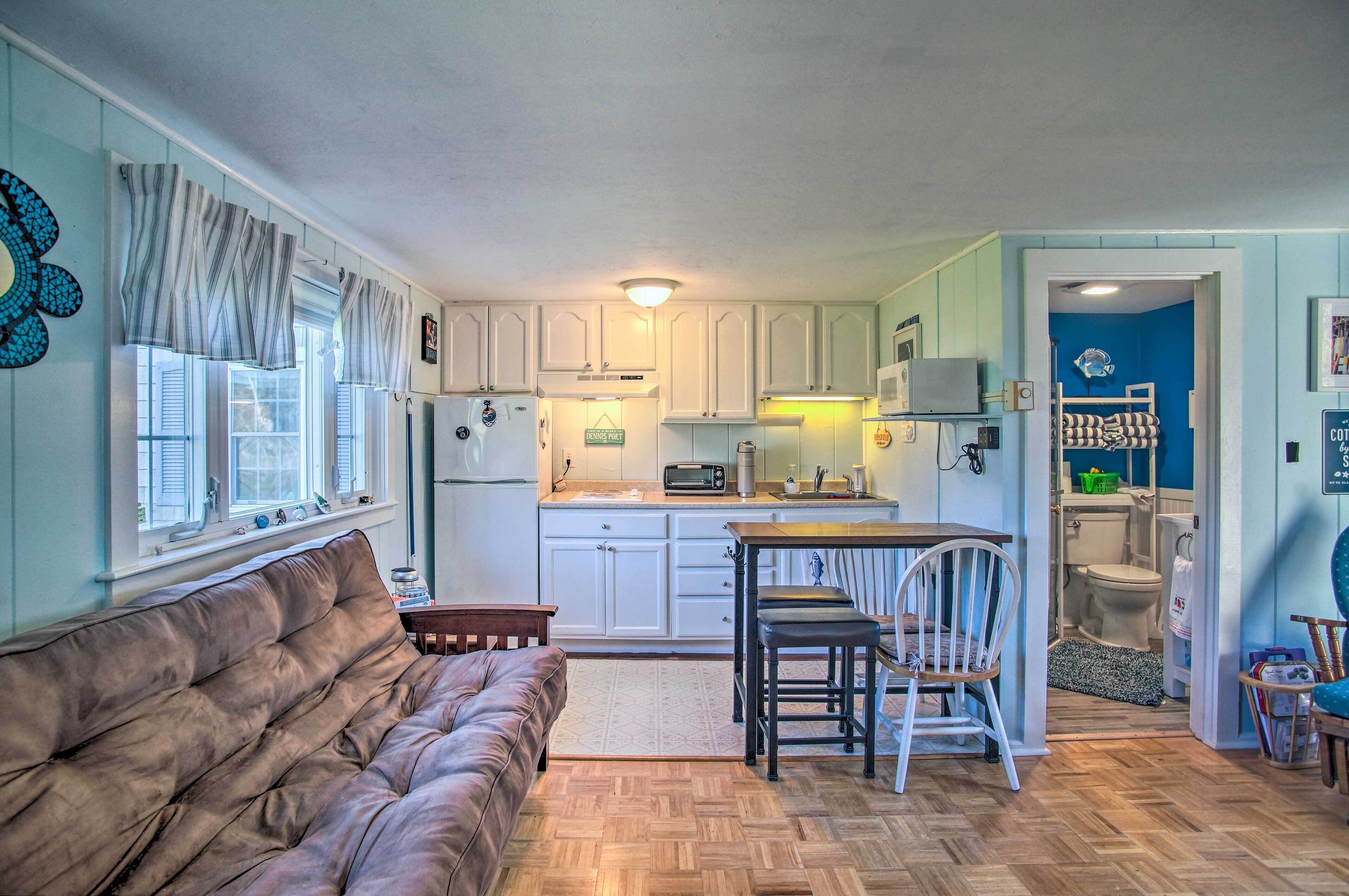 A compact living space with a kitchenette, a sofa, a dining area, and a small bathroom.