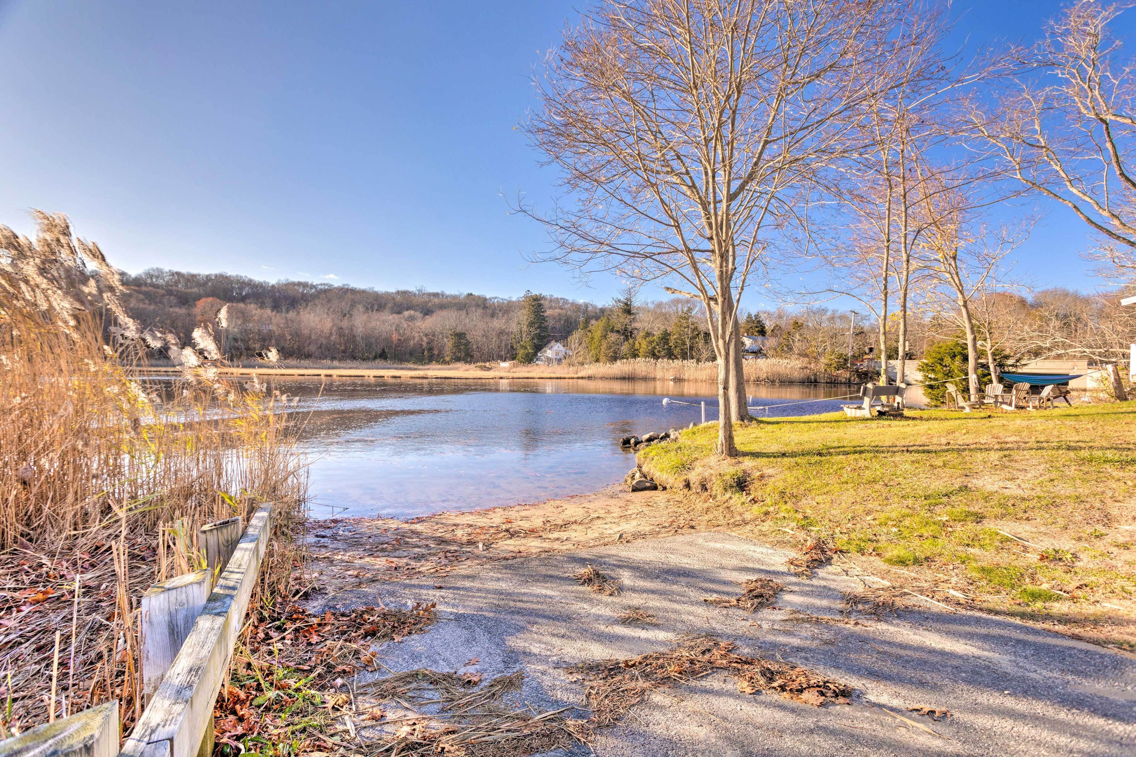A lakeside view with a wooden fence, a grassy area, and a tree.