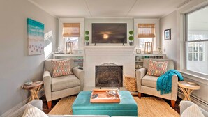 A living room with a fireplace, two armchairs, a sofa, and a coffee table. - Cozy Coastal Cottage: 5 Mi to Narragansett Beach! (Narragansett)