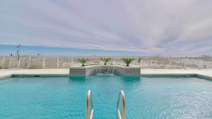 Une piscine avec vue sur la plage et une clôture en arrière-plan.