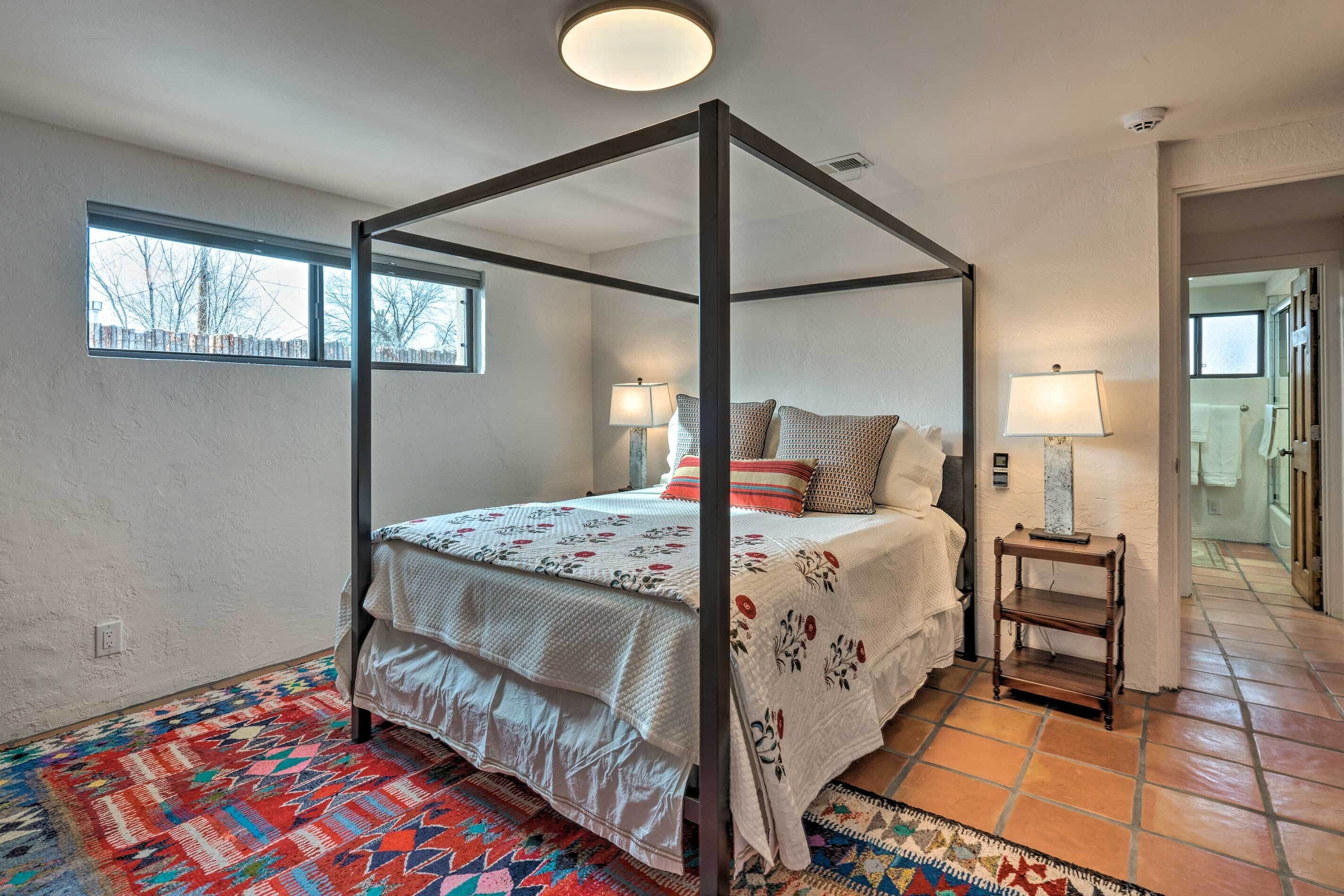 Ein Himmelbett mit Musterdecke, zwei Nachttischlampen und ein kleiner Holznachttisch.