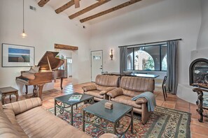 Ein geräumiges Wohnzimmer mit einem Flügel, Ledersofas und einem Kamin.