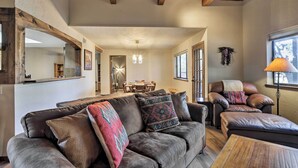 Ein gemütliches Wohnzimmer mit Ledersofa, Couchtisch und Essbereich im Hintergrund.