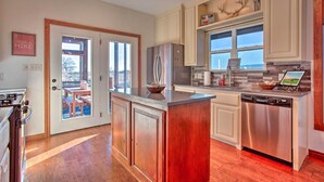 A modern kitchen with a central island, stainless steel appliances, and a view to an outdoor deck.