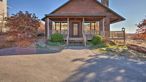 A wooden cabin with a porch, a chimney, and a stone foundation.