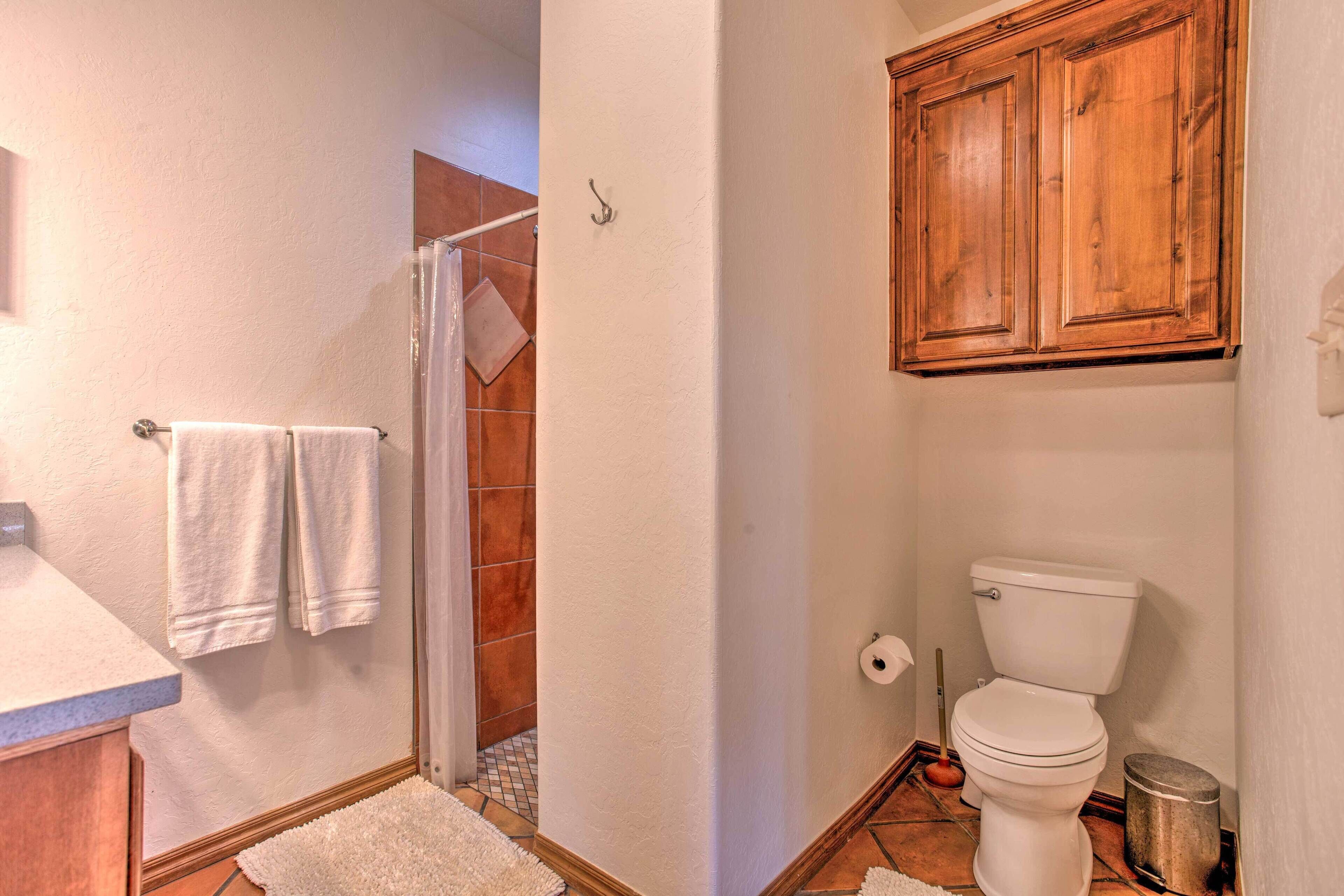 A bathroom with a shower, toilet, and wooden cabinets.