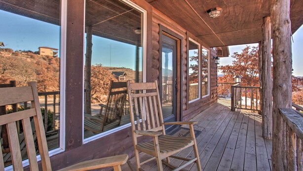 A wooden deck with a rocking chair and a bench, large windows, and a view of a hilly landscape.