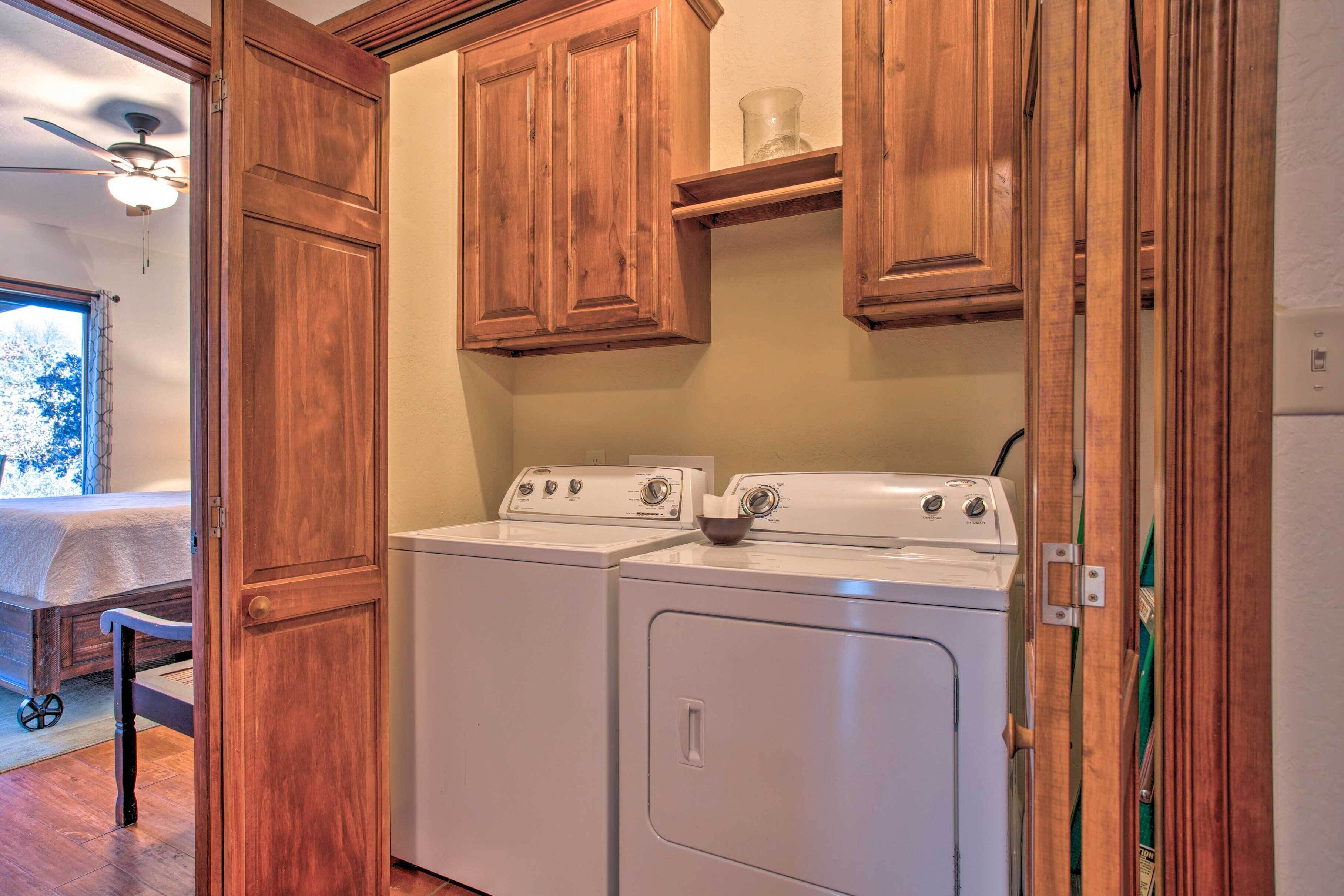 A laundry room with wooden cabinets and two white washing machines.