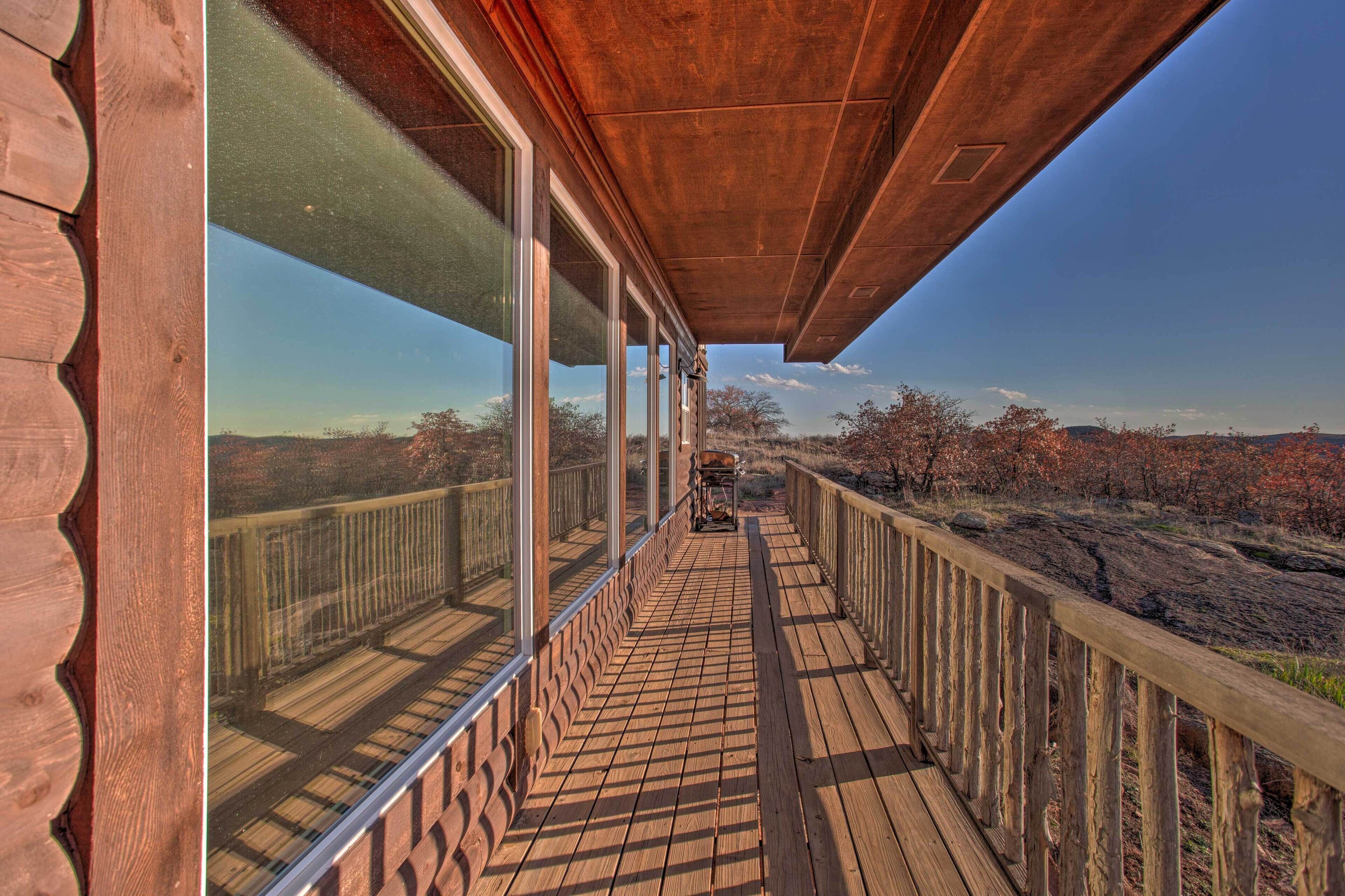A wooden deck with glass railings overlooking a natural landscape.