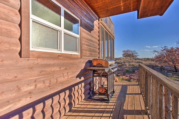 A wooden cabin with a deck, a grill, and a window overlooking a natural landscape. - Updated Cabin w/ 360-degree Mtn View: 1 Mi to Lake (Medicine Park)