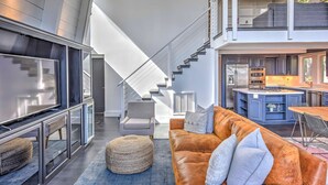 A modern interior with a staircase, a living area with a sofa and ottoman, and a kitchen area. - 10 Mi to Skiing: Tahoe City A-frame Home (Tahoe City)