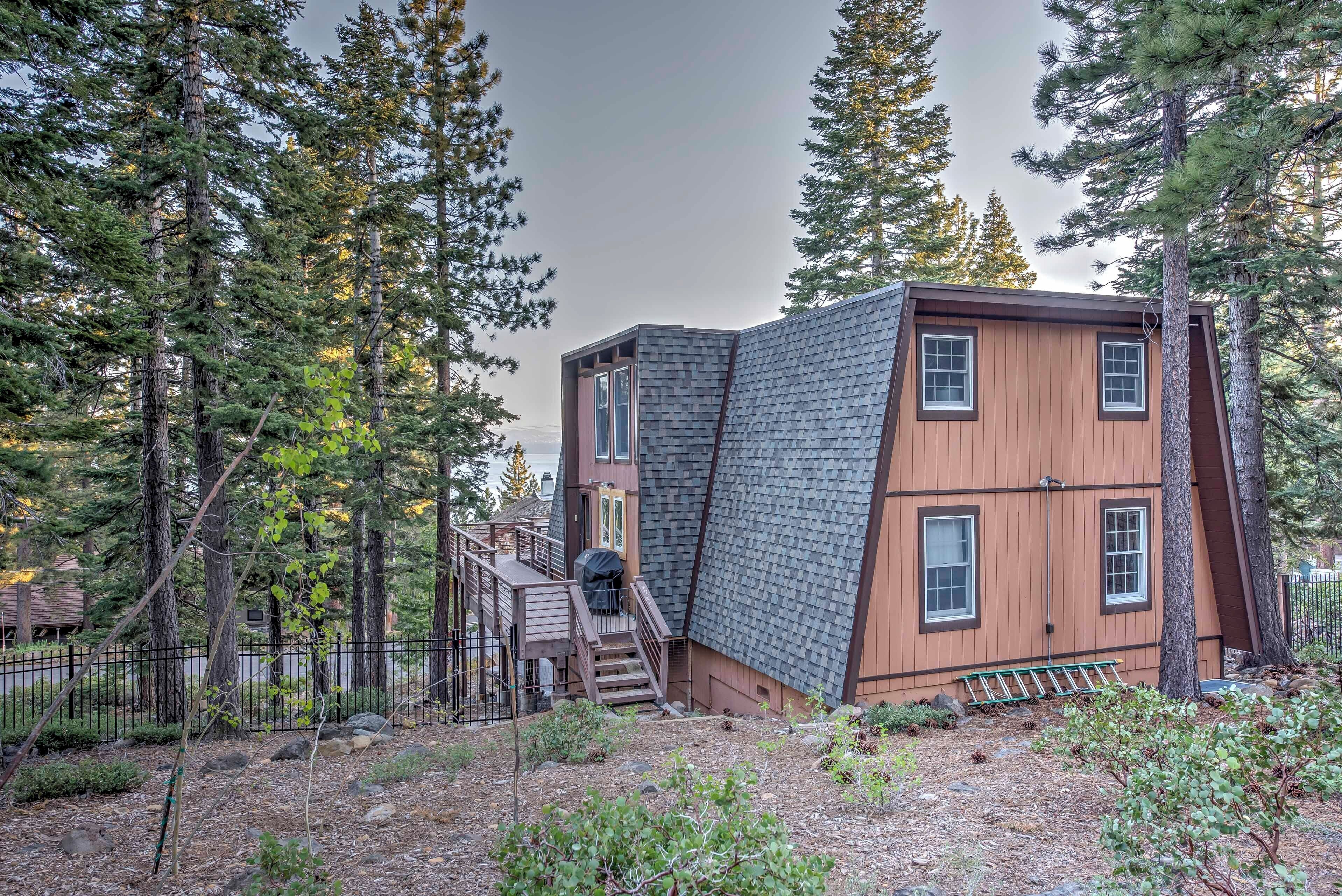 Une cabane dotée d’un toit à forte pente, d’un revêtement extérieur en bois et d’une petite terrasse avec un escalier menant à une porte.