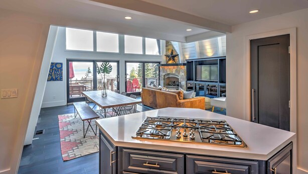 A modern kitchen with a central island, a dining area with a bench, and a fireplace. - 10 Mi to Skiing: Tahoe City A-frame Home (Tahoe City)