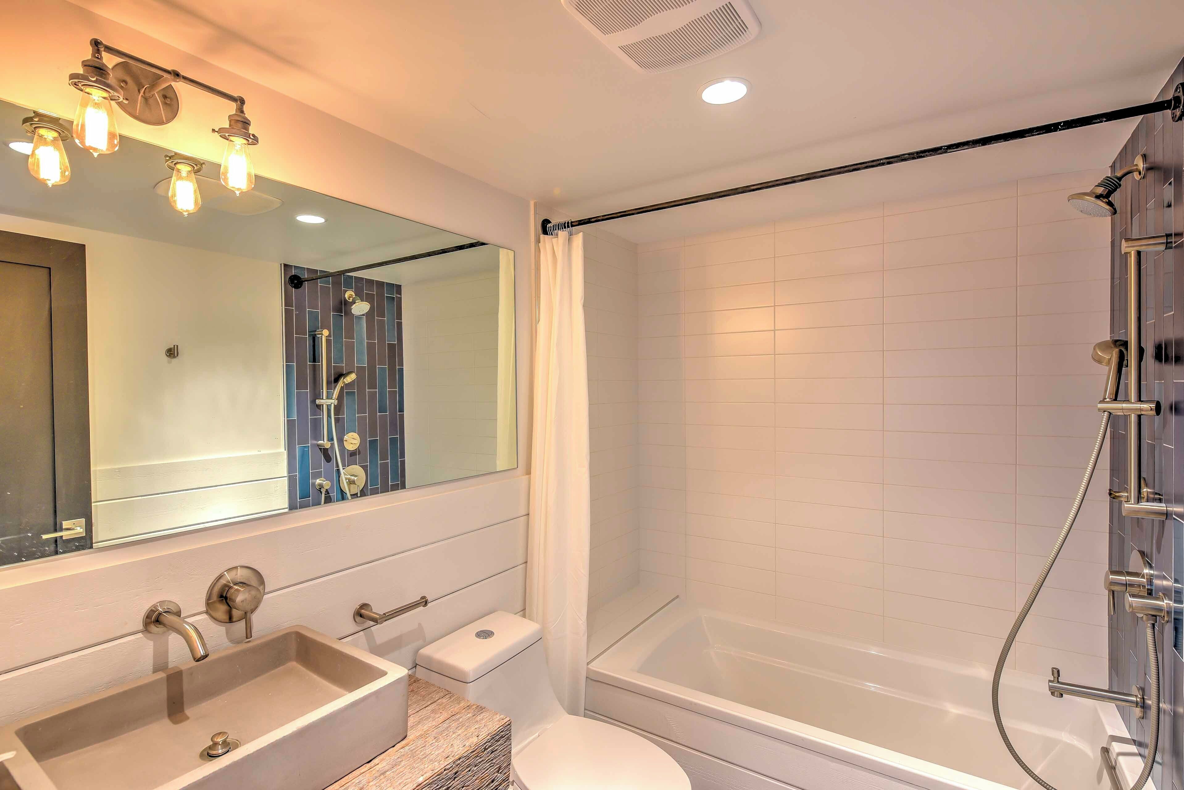 A modern bathroom with a rectangular sink, a toilet, a bathtub, and a shower.