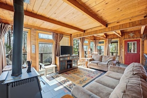 L’intérieur d’un chalet confortable, avec une cheminée, un téléviseur, un canapé et un tapis.